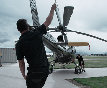 Two engineers with helicopter, one holding rotor blade