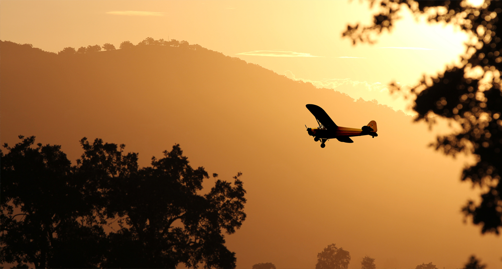 Plane against background of hills and setting sun